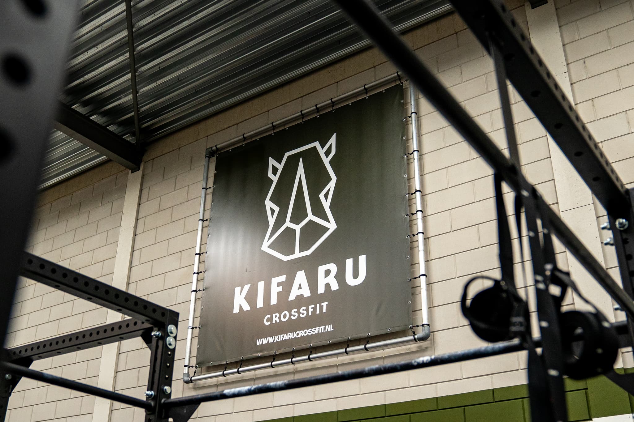 Het doek met het Kifaru CrossFit-logo aan de muur van de box in Woerden, met een rig ervoor